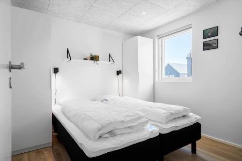 a bedroom with a bed with white sheets and a window at 944-Hvide-Sande-Langsand-143 in Hvide Sande