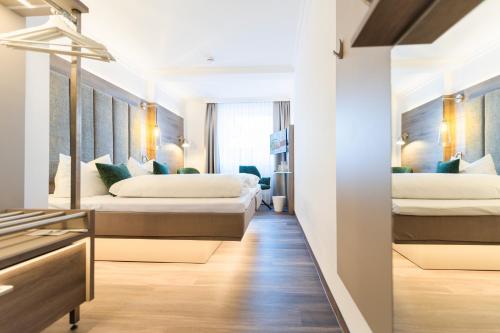 zwei Betten in einem Hotelzimmer mit Flur in der Unterkunft Hotel Hennies in Isernhagen
