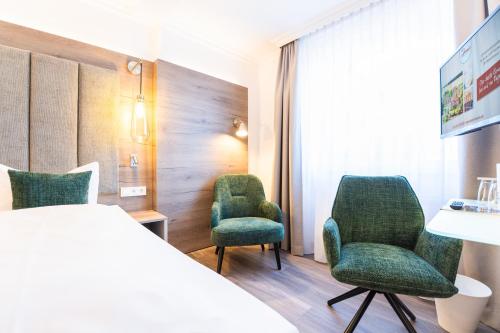 ein Hotelzimmer mit zwei Stühlen und einem Bett in der Unterkunft Hotel Hennies in Isernhagen