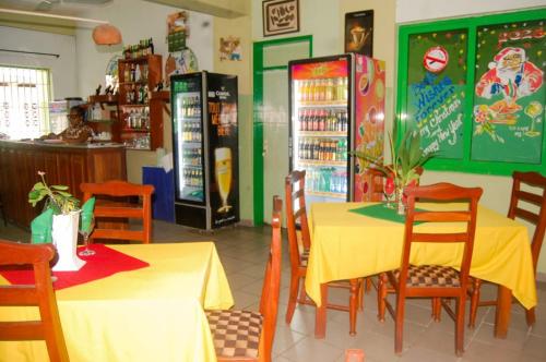 a dining room with two tables and a refrigerator at Hotel JB&G in Cotonou