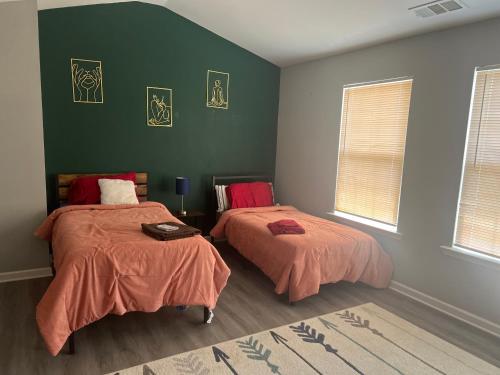 two beds in a room with green walls at Spacious 3 bedroom 3 bathroom cozy home with patio 15 mins away from ATL in Decatur