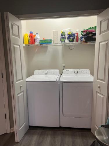 a laundry room with two washing machines and a shelf at Spacious 3 bedroom 3 bathroom cozy home with patio 15 mins away from ATL in Decatur