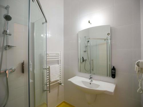 a white bathroom with a sink and a shower at ibis Styles Dunarea Galati in Galaţi