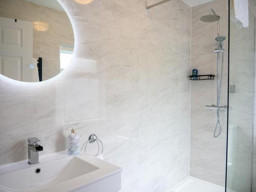 a white bathroom with a sink and a shower at Mountain View Cottages in Tralee