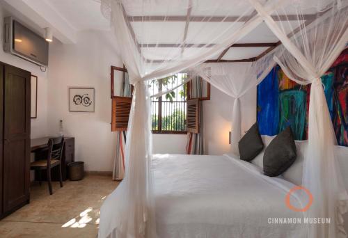 a bedroom with a white bed with a canopy at Cinnamon Museum Mirissa in Mirissa