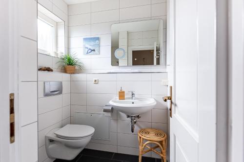 a white bathroom with a toilet and a sink at Binnendieck in Ahrenshoop