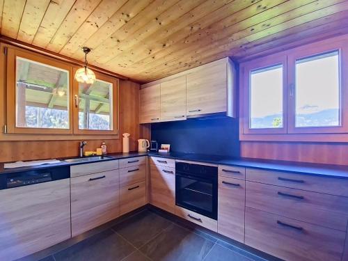 a kitchen with wooden cabinets and a sink and windows at Chalet Egg-Isch by Interhome in Grindelwald