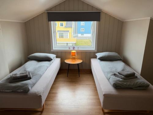 two beds in a small room with a window at Rooftop view apartment 2 in Vardø