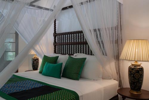 a bedroom with a canopy bed with green and white pillows at Adigars Manor Kandy - A Boutique Heritage Hotel Built in 1804 in Kandy