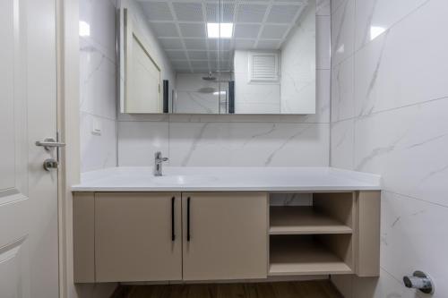 a white bathroom with a sink and a mirror at Daylights Apart Otel in Antalya