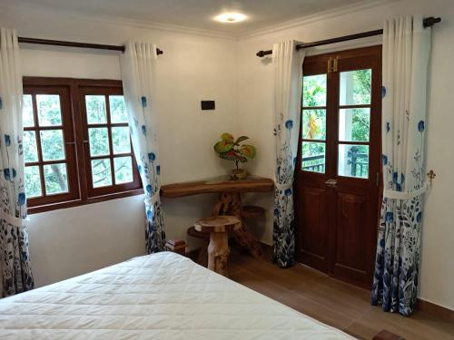 a bedroom with a bed with blue and white curtains at The Wood Cottage in Elkaduwa
