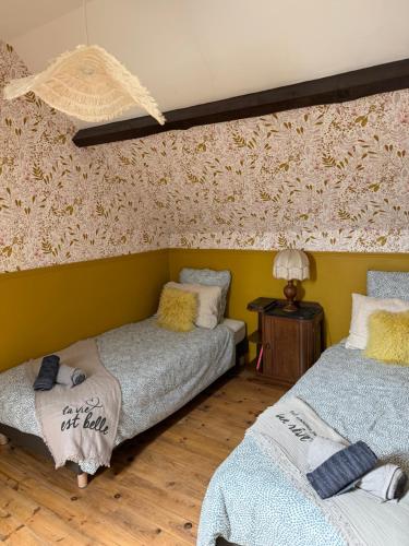 two beds in a room with a wall with flowers at Maison Bécharie in Uzerche