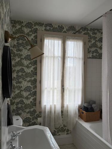 a bathroom with a tub and a window and a sink at Maison Bécharie in Uzerche