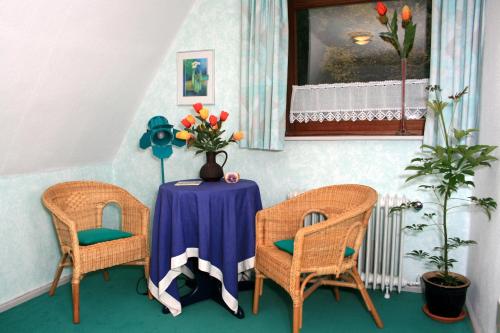 a table with two chairs and a vase with flowers at Frauenpension Arleta - Women only in Goslar