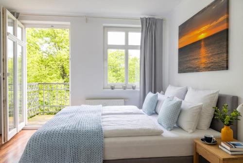 a bedroom with a bed and a large window at Stilvolles Apartment mit Wintergarten, Balkon & Parkblick - VILLA KAETHE am Kurpark in Warnemünde