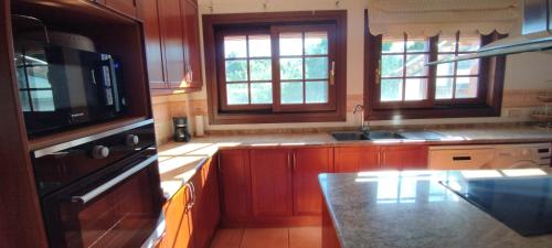 a kitchen with wooden cabinets and a sink and windows at Villa Merce in Botarell