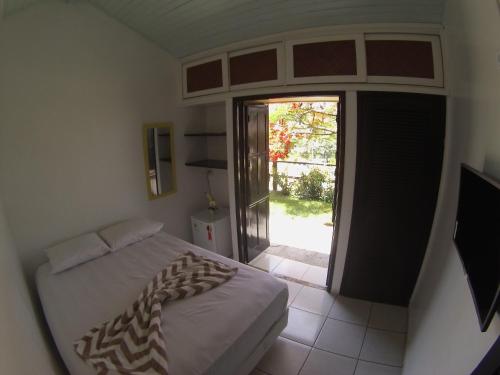 1 dormitorio con 1 cama y puerta corredera de cristal en Solar dos Anjos, en Arraial do Cabo