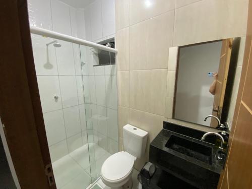 a bathroom with a toilet and a shower and a mirror at Apartamento no Crato, conforto e praticidade! in Crato