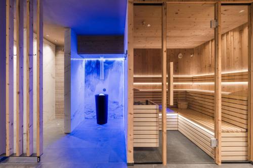 a sauna with wooden walls and a blue light at MyLiving - Hotel B&B by Majestic Resorts Dolomites in San Lorenzo di Sebato