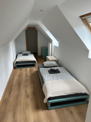 two beds in a room with white walls and wooden floors at Apartmaji Anže Kranjska Gora in Kranjska Gora