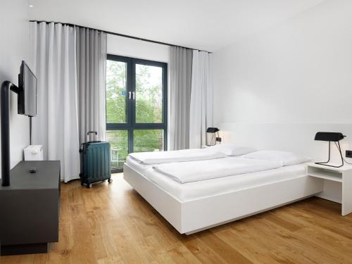 a white bedroom with a large bed and a window at smartments Berlin Karlshorst in Berlin
