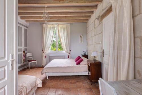 a bedroom with a bed with pink pillows on it at Le Bourg Joly in Rigny-Ussé