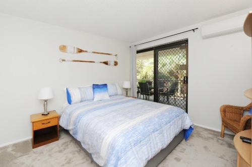 a white bedroom with a bed and a balcony at 20 Steps to the Sand! in Mooloolaba