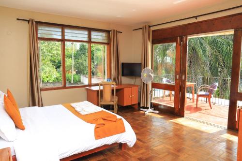 a bedroom with a bed and a desk and a balcony at Rocy Hotel in Mbale