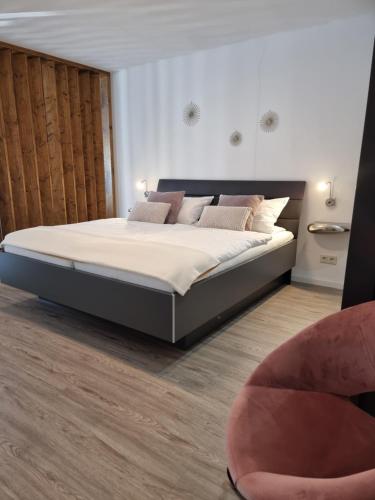 a bedroom with a large bed and a chair at Moselmoni in Bullay