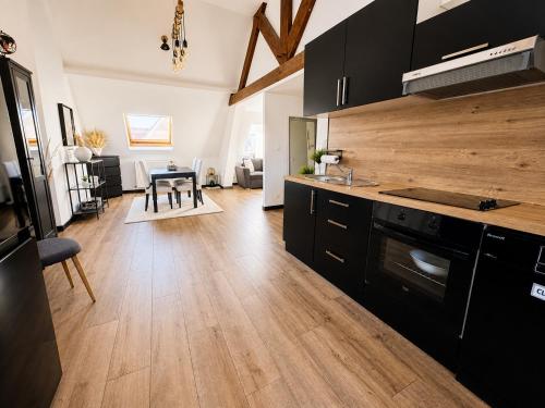 a kitchen with black cabinets and a wooden floor at Les Toits d'Arras in Arras