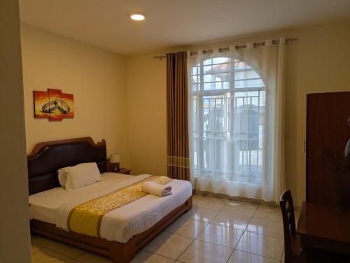 a bedroom with a bed and a large window at Gorilla Trekking Guest House in Ruhengeri