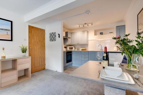 a kitchen with blue cabinets and a table with a bottle of wine at 1 Bed in West Looe oc-1west in Looe
