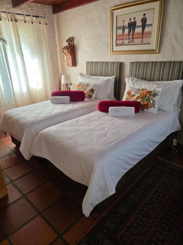 a large bed with white sheets and red pillows at Maggie Rose Cottage Self Catering in Greyton in Greyton
