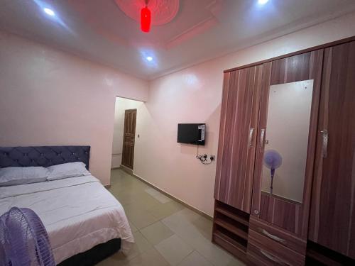 a bedroom with a bed and a cabinet and a tv at Ined Apartment Services in Ibadan