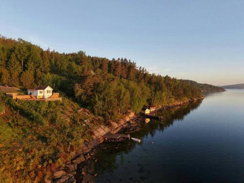 a house on the side of a river with trees at Romantic Summer House On Orust in Stillingsön