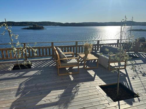 a deck with chairs and a couch on the water at Romantic Summer House On Orust in Stillingsön