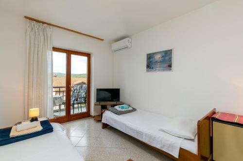 a bedroom with two beds and a tv and a window at Apartments Pino Rabac in Rabac