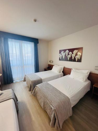 a hotel room with two beds and a window at Hotel Gallia in Pianezza