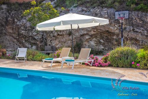 two chairs and an umbrella next to a swimming pool at Villa Rubin in Almyrida