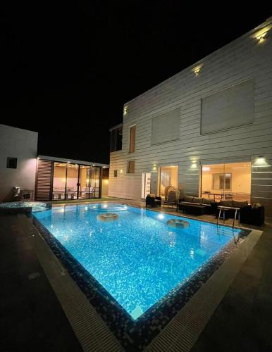 a swimming pool in front of a building at night at Villa with private Pool A in Al Khīrān