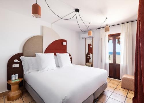 a bedroom with a white bed with a red headboard at One Shot Buenavista in Santa Eularia des Riu