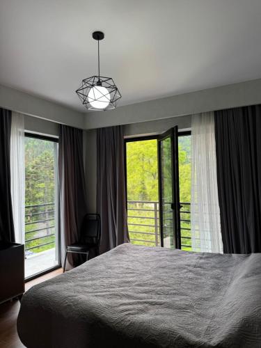 a bedroom with a bed and two large windows at Likani Stay in Borjomi