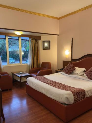 a hotel room with a large bed and a chair at Hotel Nahar Nilgiris in Ooty