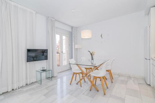 a white dining room with a table and chairs at Apartamentos Domus con parking gratuito in Granada
