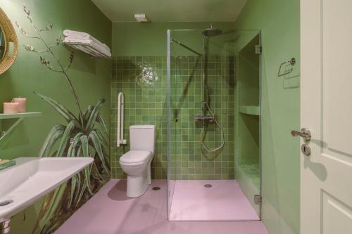 a green bathroom with a toilet and a shower at Cactus Hydra - Art Apartments in Hydra