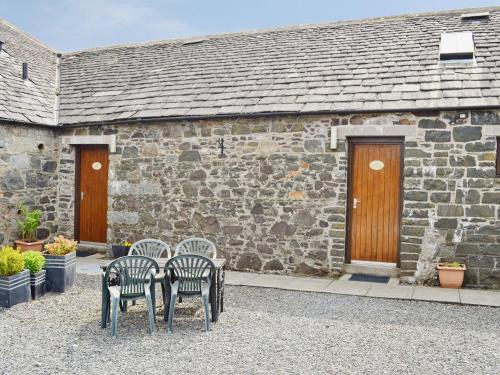 two chairs sitting in front of a stone building at The Hen Hoose in Creebridge