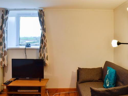 a living room with a couch and a television at The Hen Hoose in Creebridge