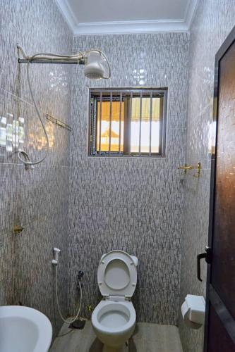 a bathroom with a toilet and a sink and a window at Marindo Lodge Moshi in Moshi