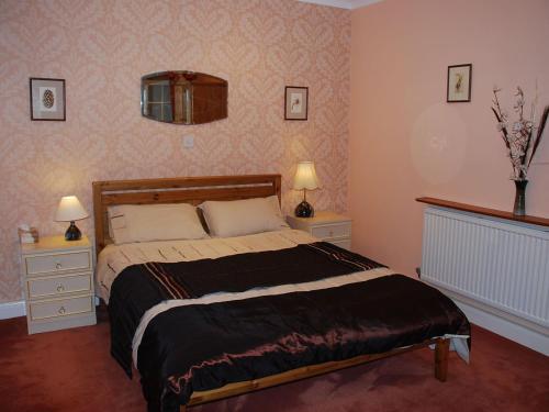 a bedroom with a bed with two night stands and two lamps at The Pottery Annexe in Baslow