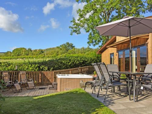 a patio with a table and chairs and an umbrella at Ash Lodge At Lon Lodges in Nantmel